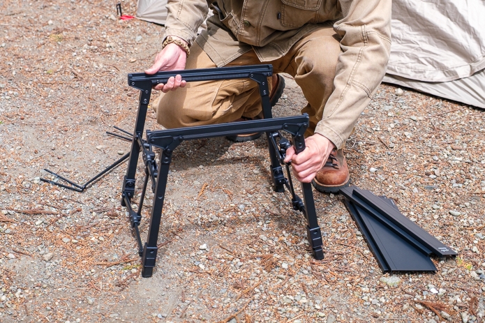 小型テーブルをテントの前で組み立てる男性
