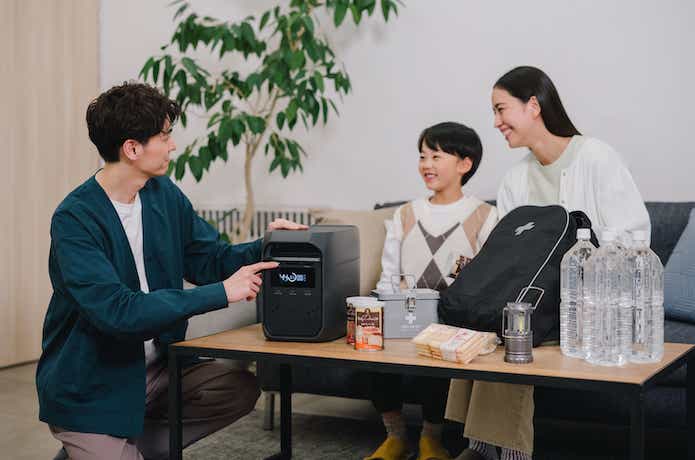 家でポータブル電源を囲んで防災について話している家族