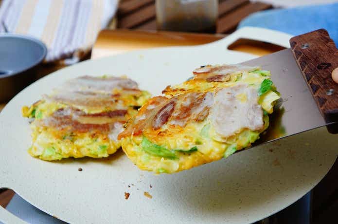 キャンピングムーンのスクレーパーでお好み焼きをグリドルから取り分ける様子