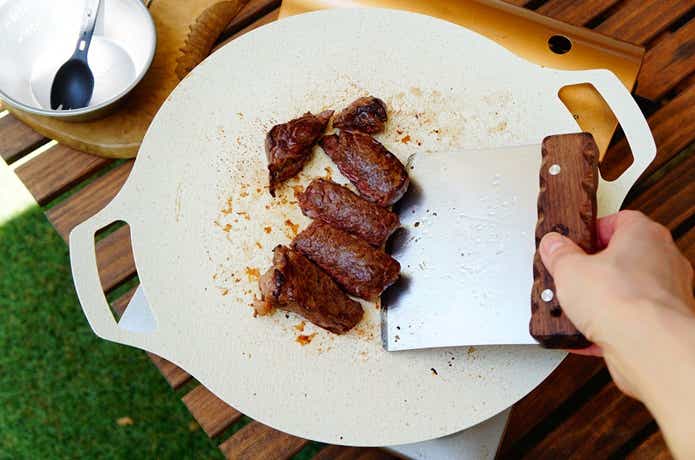 キャンピングムーンのスクレーパーでカットしたステーキ肉をグリドルから取り分ける様子