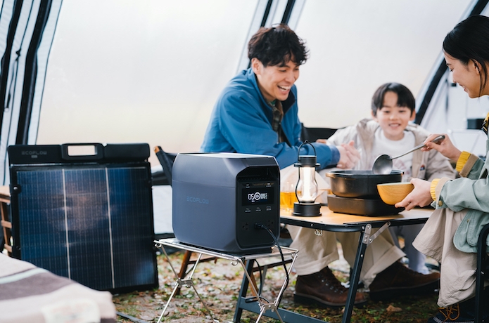 テントの中でポータブル電源を囲んで鍋を食べる家族