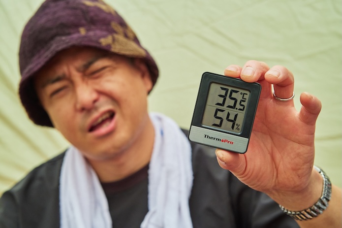 温度計を持って暑そうな顔をしている男性