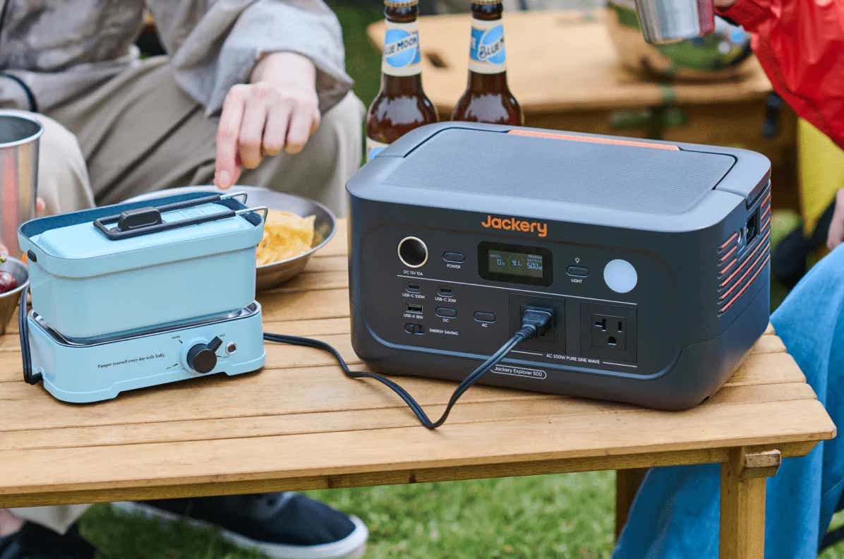 屋外でポータブル電源に家電を繋ぎ料理をしている様子
