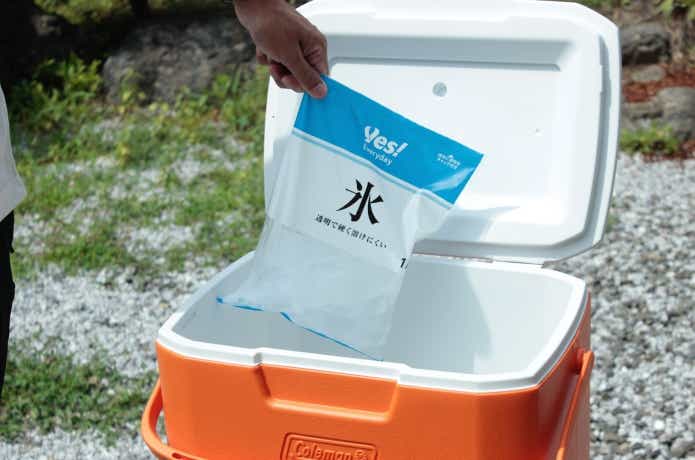 溶けたロックアイスの袋をクーラーボックスから取り出しているところ　