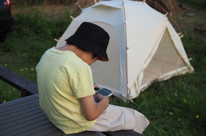 キャンプ場でスマホ見る子ども