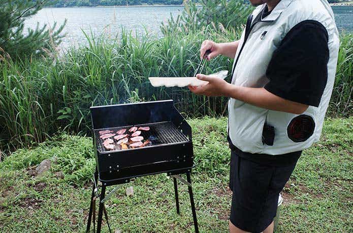 BBQコンロ前でお肉のパックを持った男性