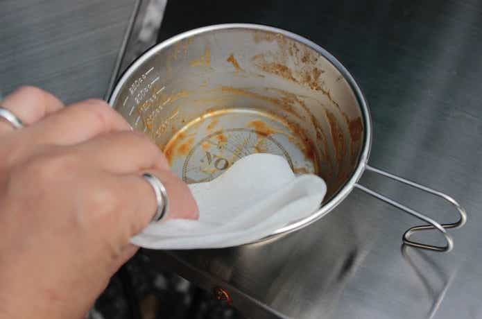 食器用汚れふきシートでシェラカップの油汚れを拭き取っているところ