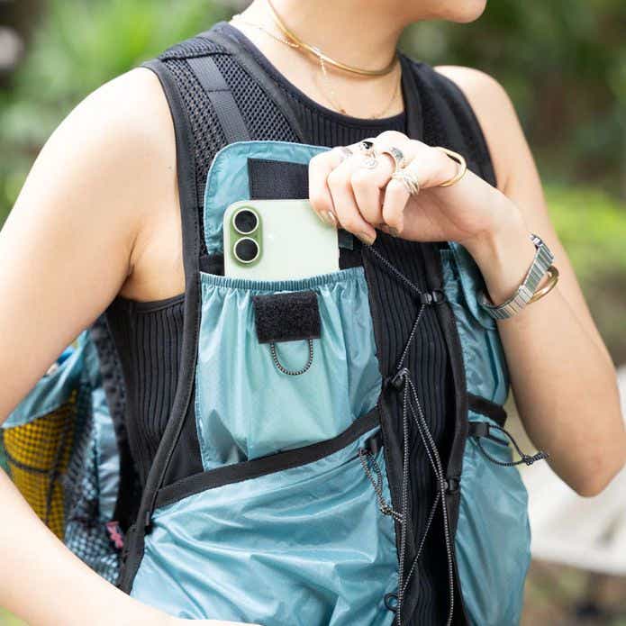 コブマスター「HUMMING PACK VEST」に収納したスマホを取り出す女性