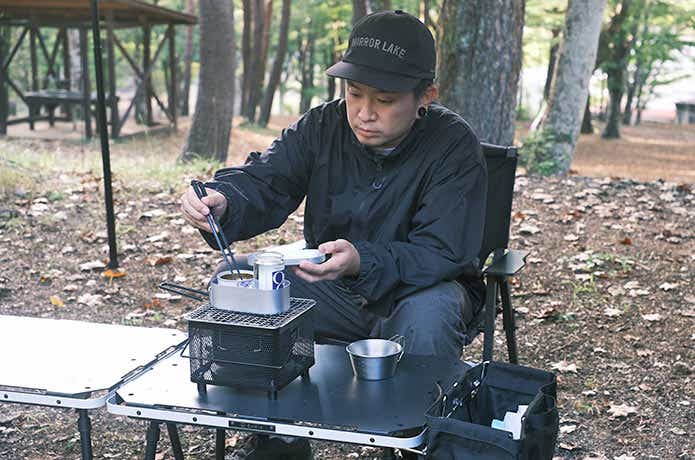 卓上キューブコンロで温めた鯖缶を食べる男性