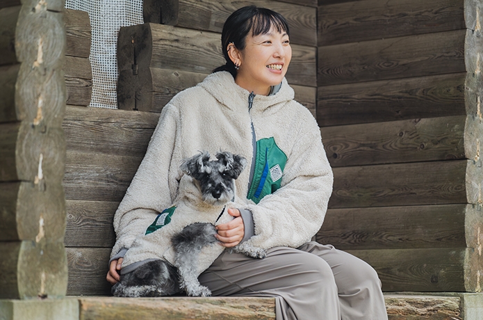 DOGひっくりベストを着てベンチに座る女性と愛犬